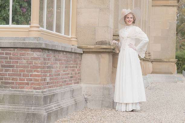 Chic victorian woman with hat walking along mansion.