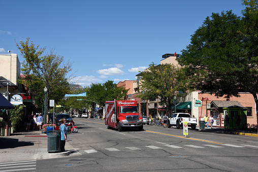 Durango, United States - September 11, 2015: Looking north along Main Avenue, Durango, Colorado, USA, at the junction with 7th Street. A variety of commercial properties catering to local and tourist trade line the street. A Budweiser delivery truck approaches a pedestrian crossing where a woman is waiting. Unidentified people.