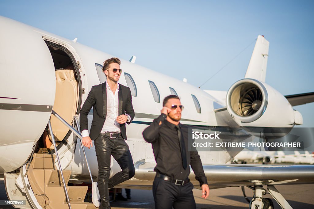 Famous person with bodyguard leaving the jet airplane Male celebrity exiting the private jet airplane in the escort of his bodyguard dressed in black. Airport Stock Photo