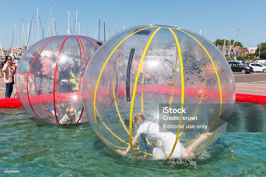 Children have fun inside plastic balloons on the water Urk, The Netherlands - May 31, 2014: Children have fun inside big plastic balloons on the water during a fishing fare at the harbor of Urk Inflatable Stock Photo