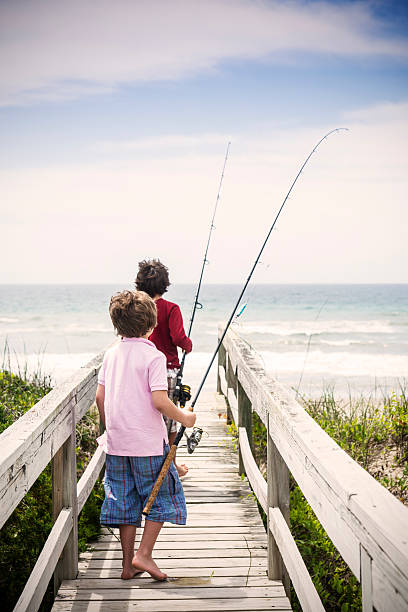 Heading to do some surf fishing on the Outer banks Two brothers heading out with fishing rods to do some fishing on the beach in North Carolina. sea fishing stock pictures, royalty-free photos & images