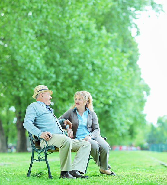 istock Mature couple talking seated on bench in park 495385637