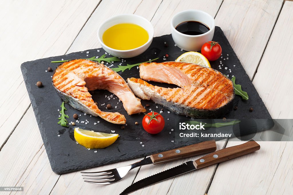 Grilled salmon, salad and condiments Grilled salmon, salad and condiments on wooden table Grilled Salmon Stock Photo
