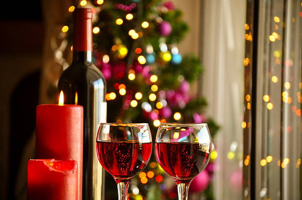 istock Red wine on table Christmas tree in background 495393234