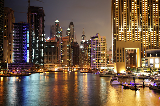 Scenic view of illuminated Dubai city at night with boats, United Arab Emirates