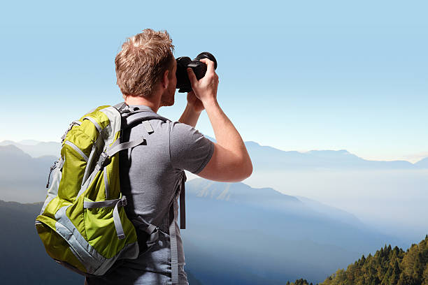 istock Young man taking photo on top of mountain 495421249