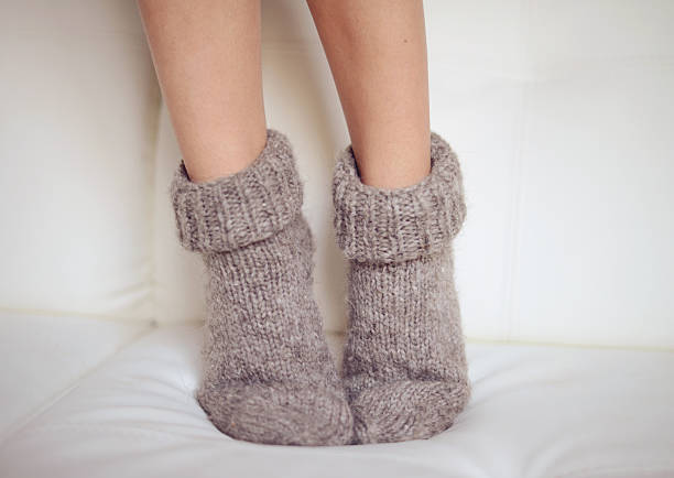 Feet in wool socks warming at the fireplace with coffee