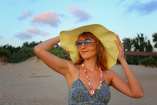istock Young beautiful girl in a hat standing on the beach 495435592