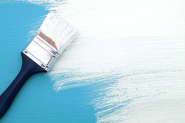 istock Paintbrush with white paint painting over blue 495436050