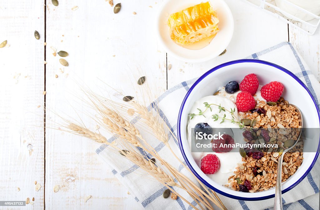 Healthy breakfast. Granola with pumpkin seeds, honey, yogurt ,fresh berries. Healthy breakfast. Granola with pumpkin seeds, honey, yogurt and fresh berries in a ceramic bowl on white background. 2015 Stock Photo