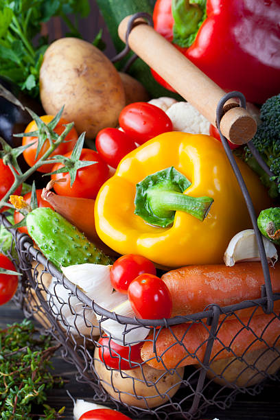 Vegetables variety in a wire basket on a wooden background. Copy space