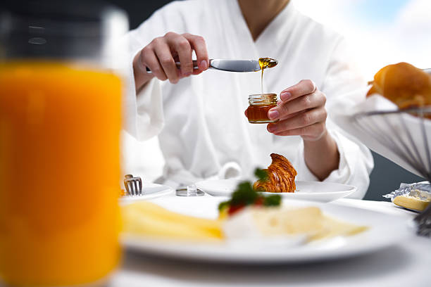 Breakfast in Room Woman eating breakfast in a hotel room. room service stock pictures, royalty-free photos & images