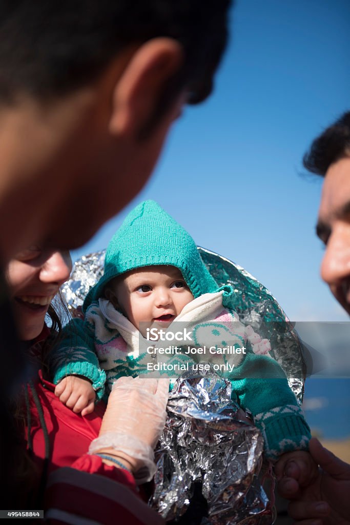 Volunteers holding Kurdish baby on Lesbos Lesbos, Greece - October 25, 2015: Ala, 10 months old and from Qamishli, Syria, is held by volunteers who greeted and assisted her family and others as they reached the coast of Lesbos at the end of a dangerous boat ride from Turkey. The family is Kurdish. Immigrant Stock Photo