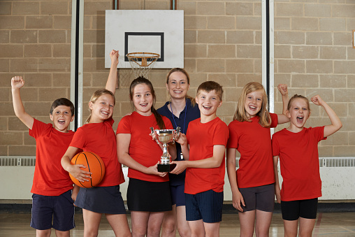 Victorious School Sports Team With Trophy In Gym