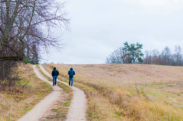 istock Two men walking by the bent rural road 495471568