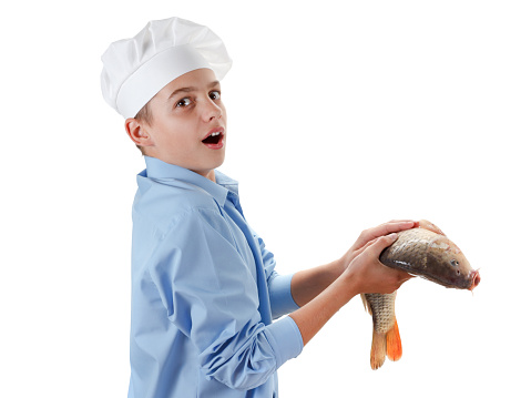 Young caucasian chef holding a fish carp. Hilarious cooking wholesome food. Isolated on white background
