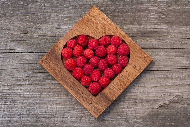 istock Raspberry in wooden heart-shaped box on wooden background 495478628
