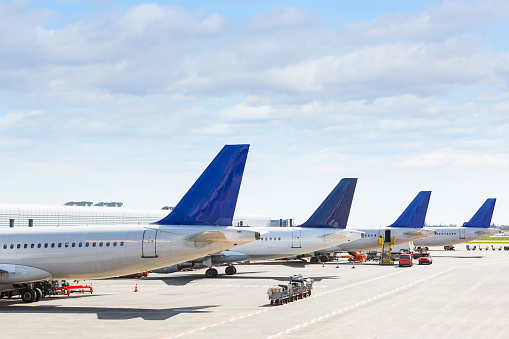 Tails of some airplanes at airport during boarding operations. They are four planes on a sunny day, with a blue sky. Travel and transportation concepts.