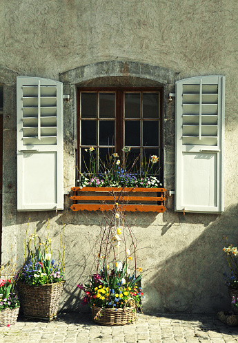 rustic window with old wood shutters and flower pots in stone rural house, Switzerland. Toned image