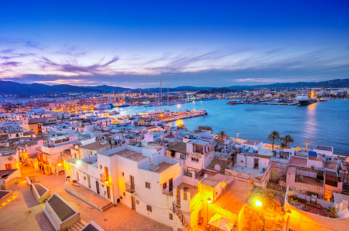 Elevated view over Ibiza Old Town and Harbour with ferries at dusk.