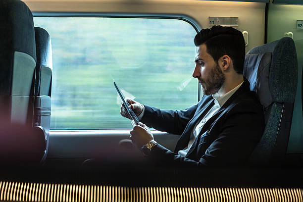 Bussinesman seating on a train beside window and working stock photo