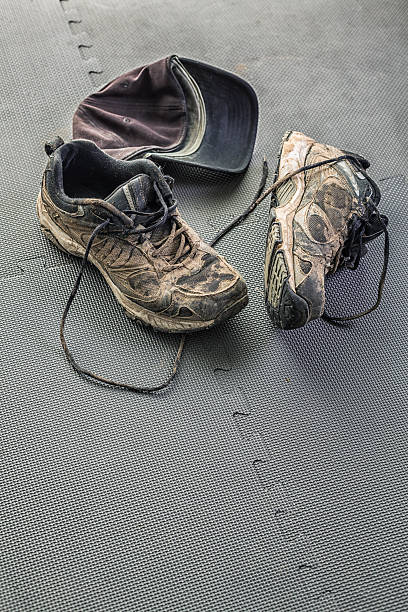 istock Muddy Worn Athletic Running Sneaker Shoes And Baseball Cap 495495042