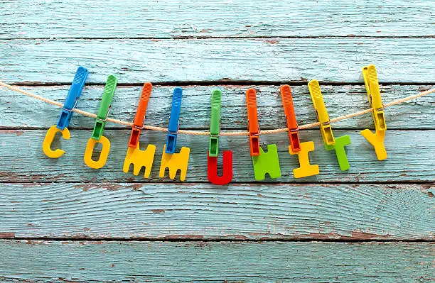 word community fasten clothespins on a rope behind a wooden background