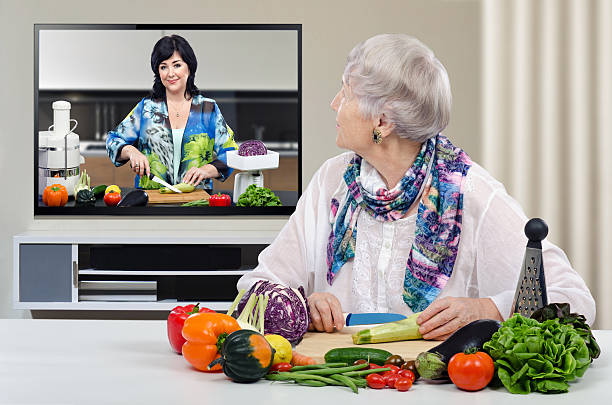 Grey haired aged woman is cutting vegetables stock photo