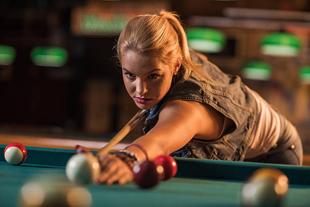 Young beautiful woman playing billiard in a pool hall.