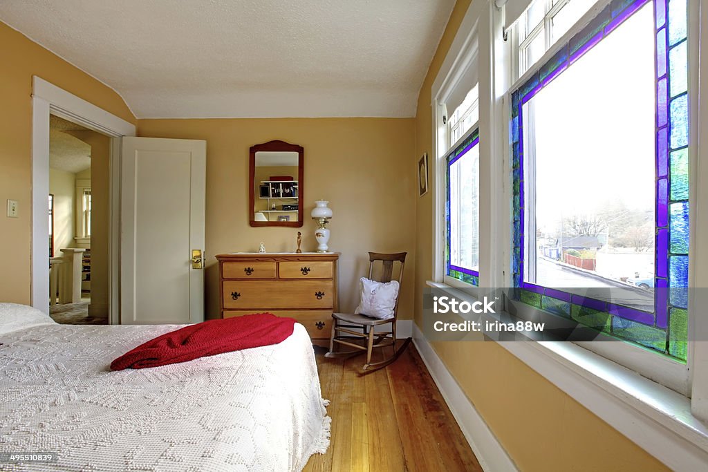 Yellow bedroom with white bed and wood dresser. English old bedroom with yellow walls and white bed. Apartment Stock Photo