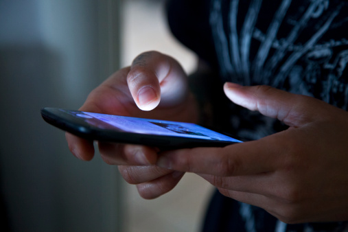 Hands holding smartphone in the dark. 