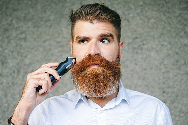 Portrait Of Bearded Man Trimming His Beard Portrait of bearded man trimming his beard. bushy stock pictures, royalty-free photos & images