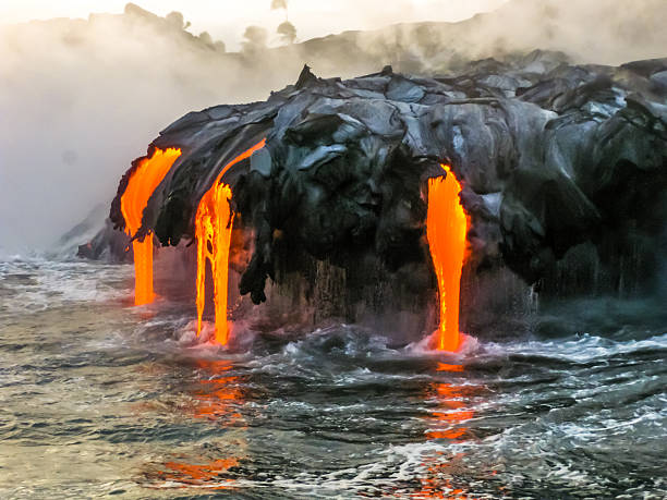 Volcano Sea view of Kilauea Volcano in Big Island, Hawaii, United States. A restless volcano that has been in business since 1983. Shot taken at sunset when the lava glows in the dark as jumps into the sea. kīlauea volcano photos stock pictures, royalty-free photos & images