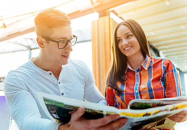istock Young couple reading newspaper and drinking coffee in modern cafe 495524562