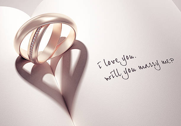 3D abstract wedding rings with heartshadow on a book middle abstract wedding rings with heartshadow on a book middle with i love you will you marry me card text diamond shaped photos stock pictures, royalty-free photos & images