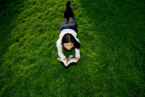 istock young female student reading textbook outside in grass 495541101