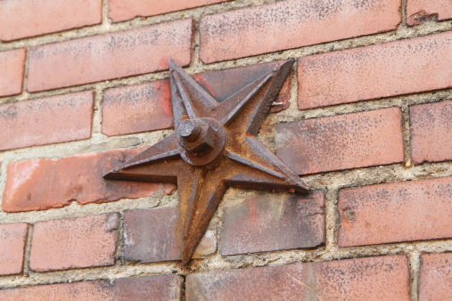 Old rusty star washer used to strengthen old building's stability.