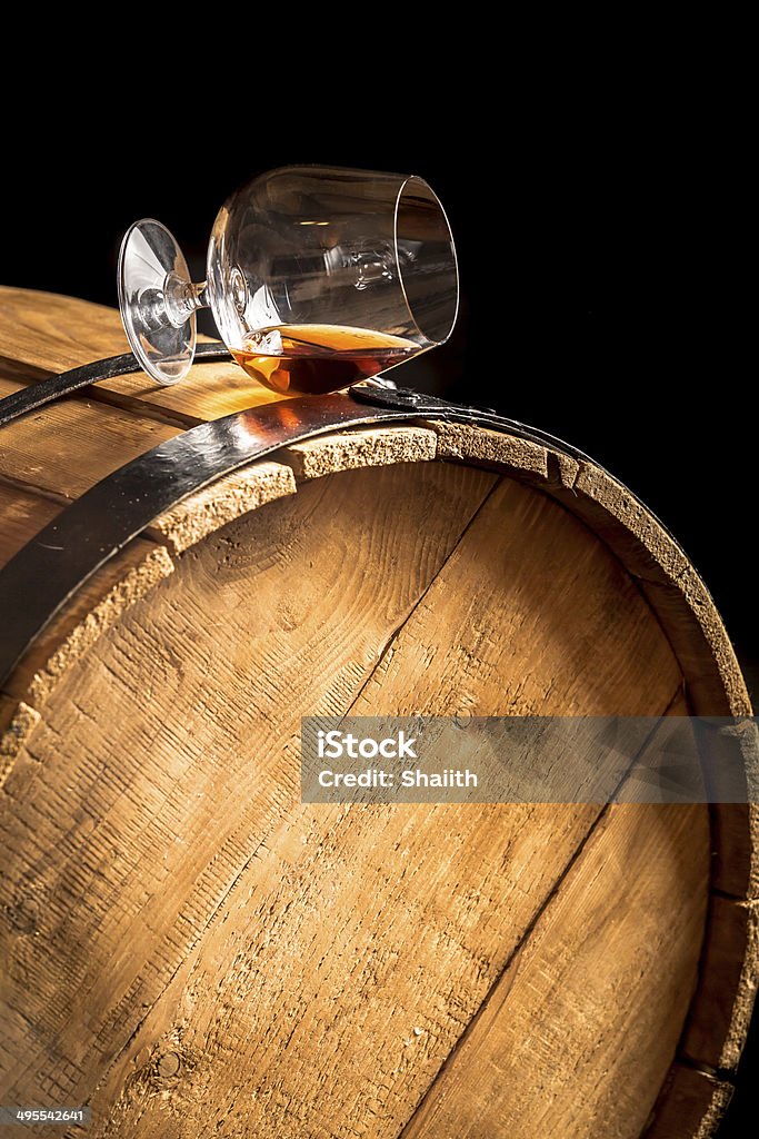 Glass of cognac on the old wooden barrel Whiskey Stock Photo