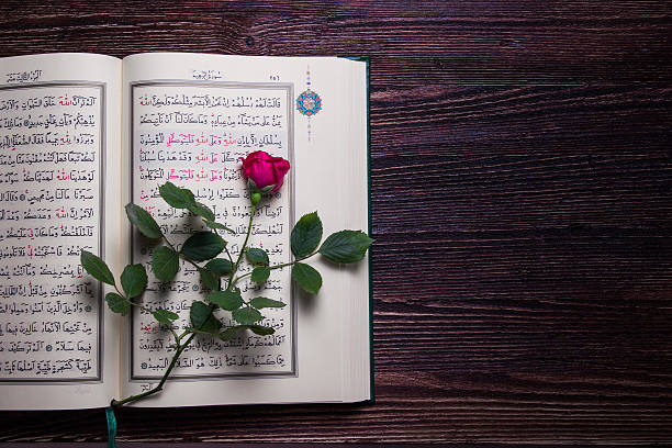 istock Kuran on the wood table with red rose. 495543563