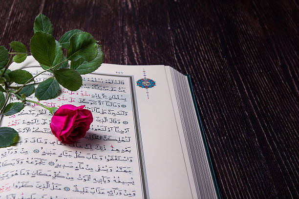 istock Kuran on the wood table with red rose. 495543573