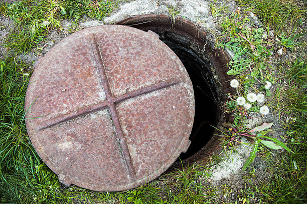 istock Open manhole with rusty metal cover in the grass. 495547753
