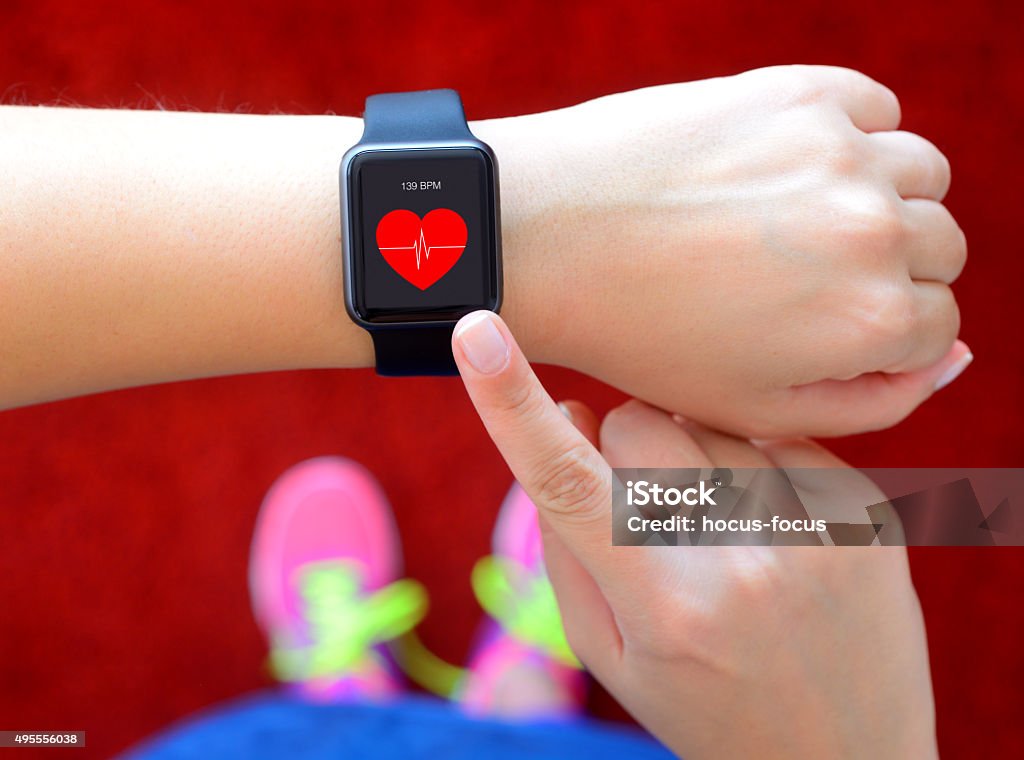 Smart watch displaying heart rate while exercising Runner using smart watch with heart rate application on a running track. Smart Watch Stock Photo