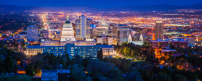 Blue dusk skies over the city lights and landmarks of Salt Lake City, the monument spotlit dome of the State Capitol and the ornamental spires of the Mormon Temple surrounded by the skyscrapers of downtown, Utah, USA. ProPhoto RGB profile for maximum color fidelity and gamut.