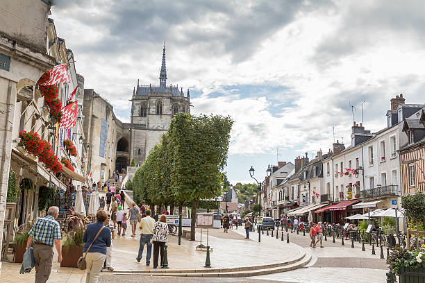 Amboise, France - August 20, 2015: Place Michel Debre - Amboise  - Loire Valley - France - Some people walking on town square where is located the main entrance of the Royal Chateau of Amboise. On the left many shops and restaurants. Amboise is a commune in the Indre-et-Loire department in central France. It lies on the banks of the Loire River, 17 miles (27 km) east of Tours