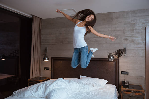 istock Happy young woman jumping on bed 495560762