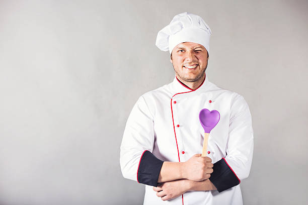 istock Young chef holding heart shaped spoon and winking 495561340