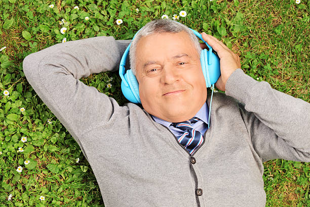 istock Mature man with headphones lying on grass 495569069
