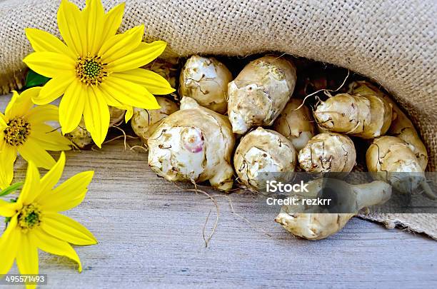 Jerusalem Artichokes With Burlap And Flowers On Board Stock Photo - Download Image Now