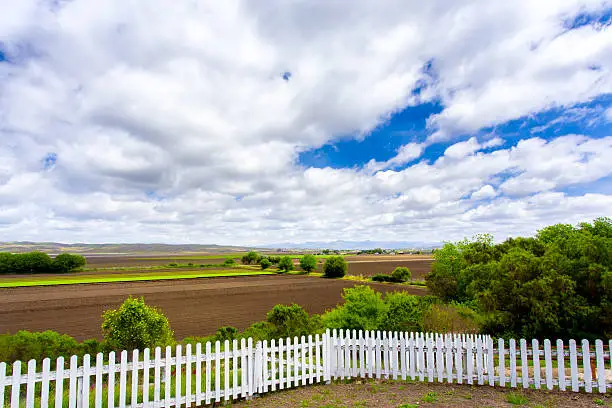 White Picket Fence  Green Farmland and Dramatic Clouds.