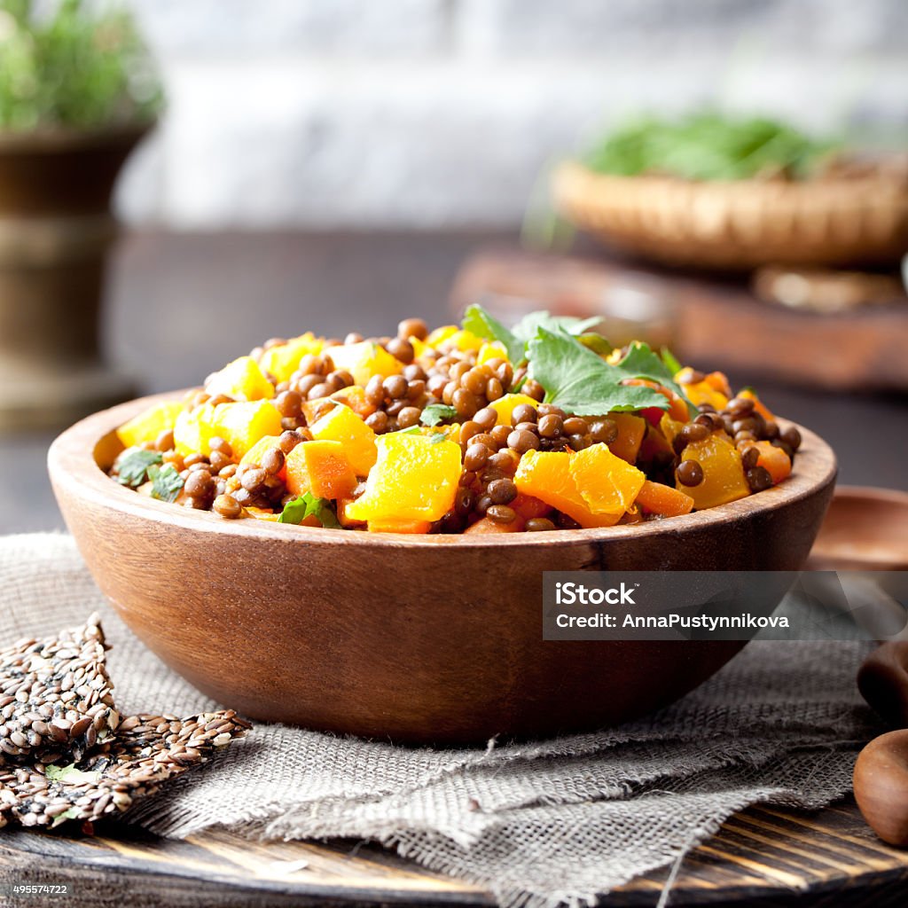 Lentil with carrot and pumpkin ragout in a wooden bowl. Lentil with carrot and pumpkin ragout in a wooden bowl on a wooden background Lentil Stock Photo